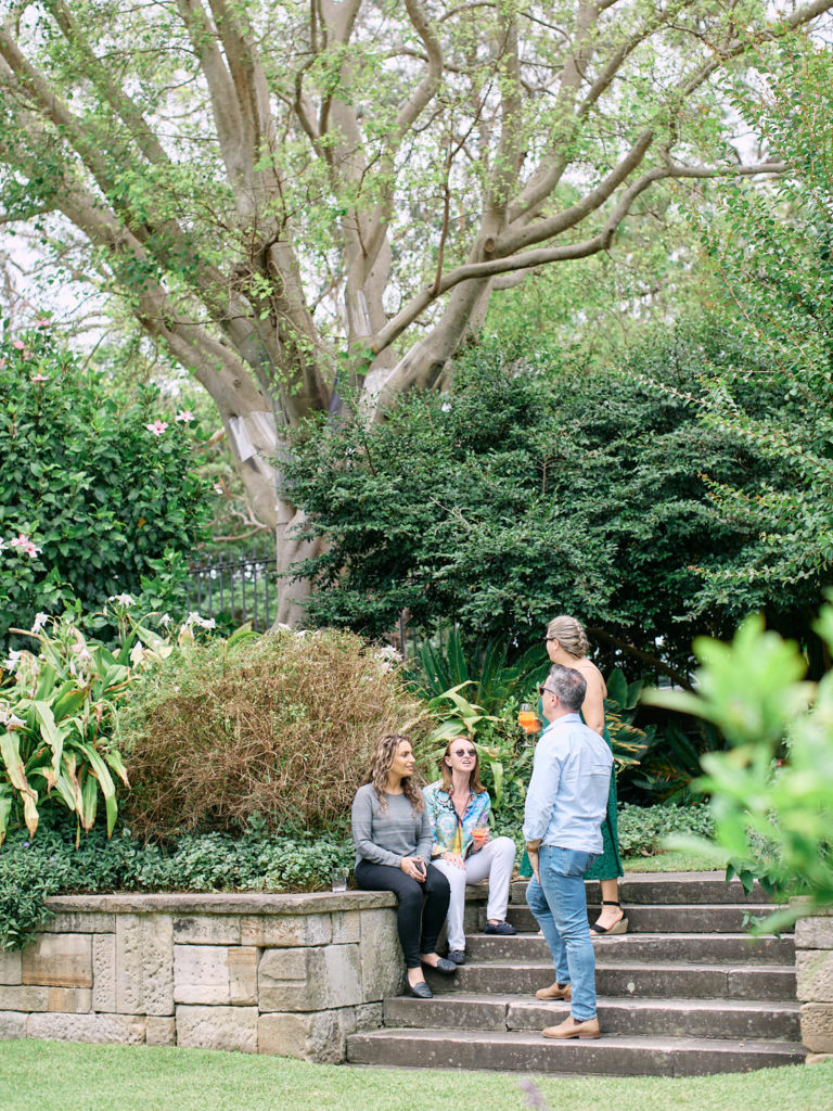 Group of people sitting on steps in garden talking