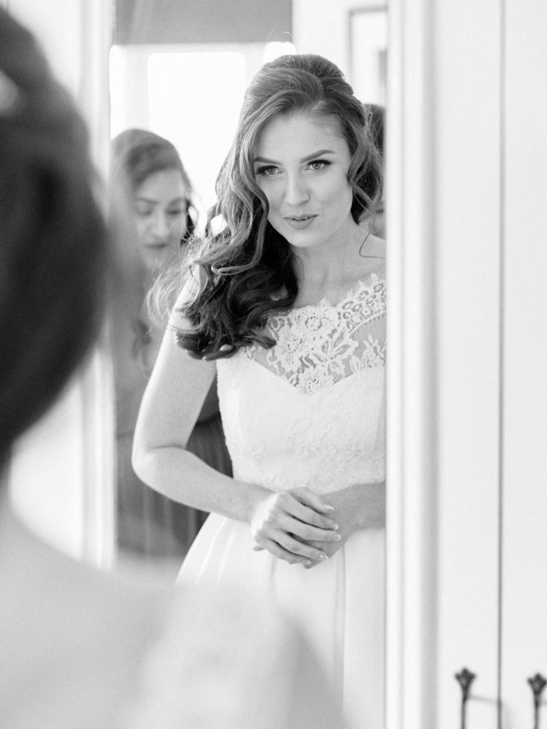 Bride with wedding dress on taking a breath in front of mirror
