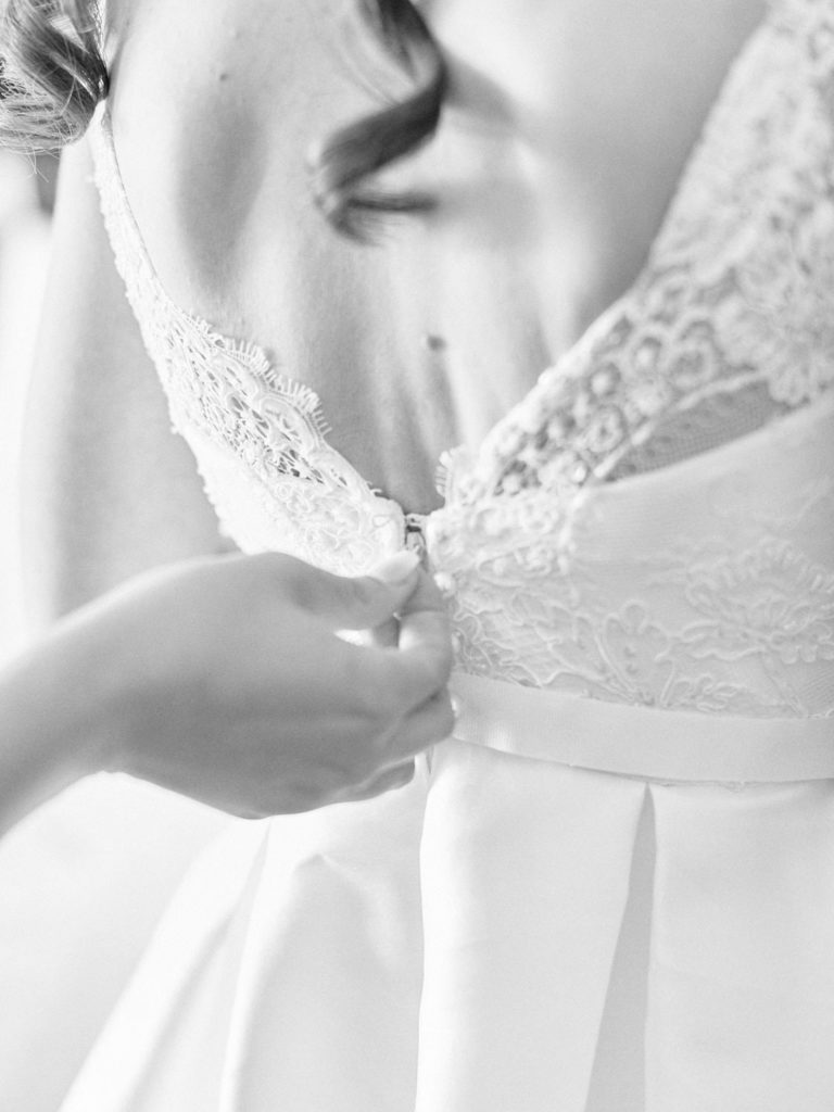 Close up detail of brides dress being zipped up