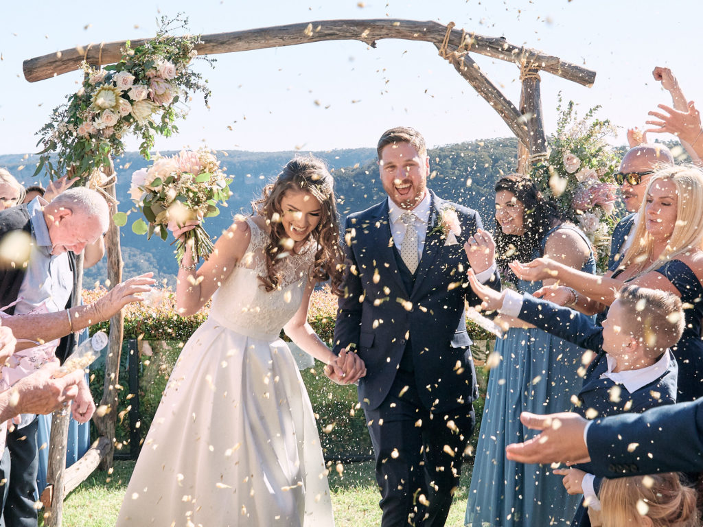 Newlywed recessional being showered by petals on lawn of their Echoes Boutique Hotel wedding