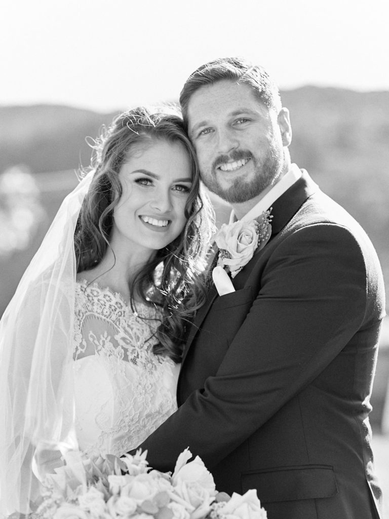 Black and white portrait of newlyweds smiling at camera