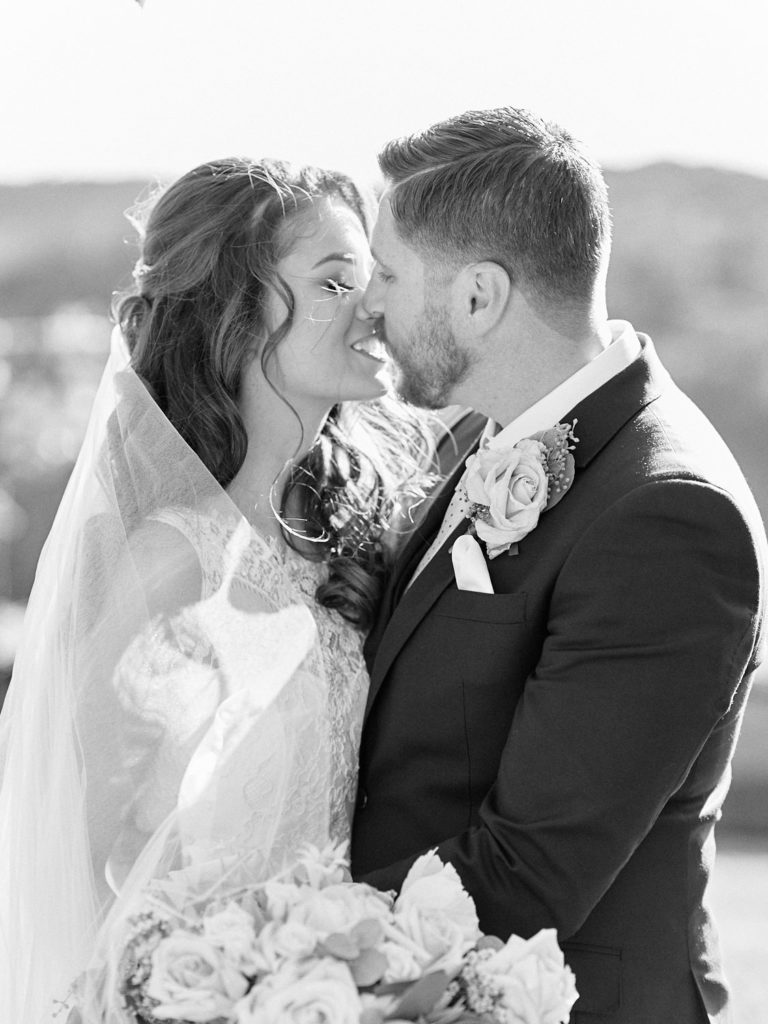 Black and white portrait of bride and groom kissing