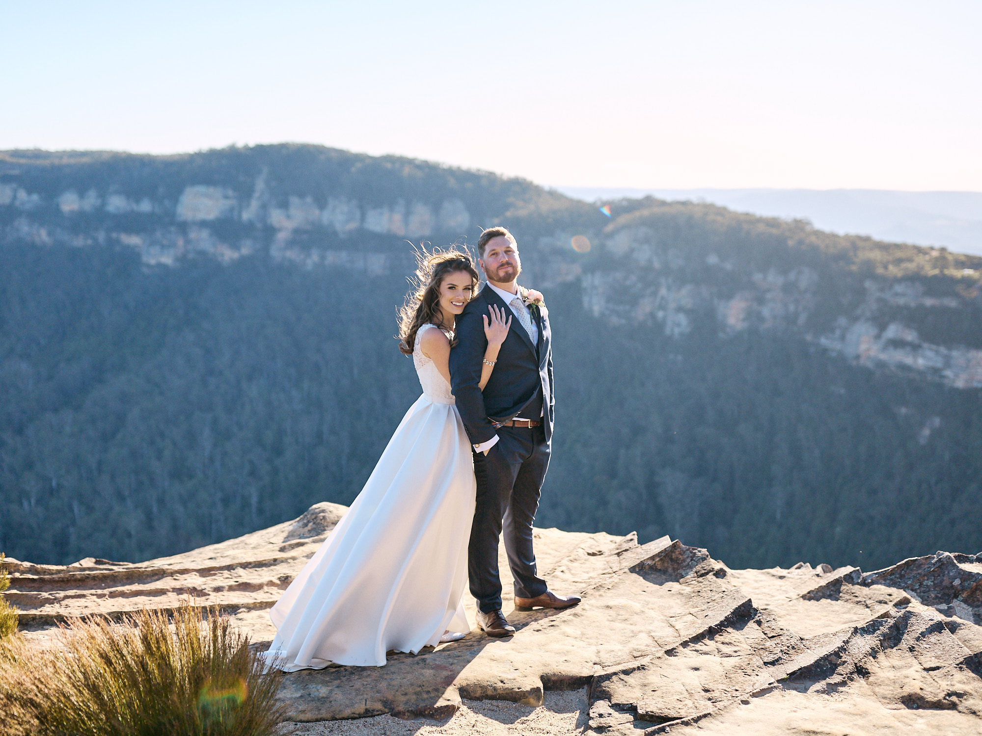 Bride cuddling groom at Lookout in Blue Mountains during their Echoes Boutique Hotel wedding
