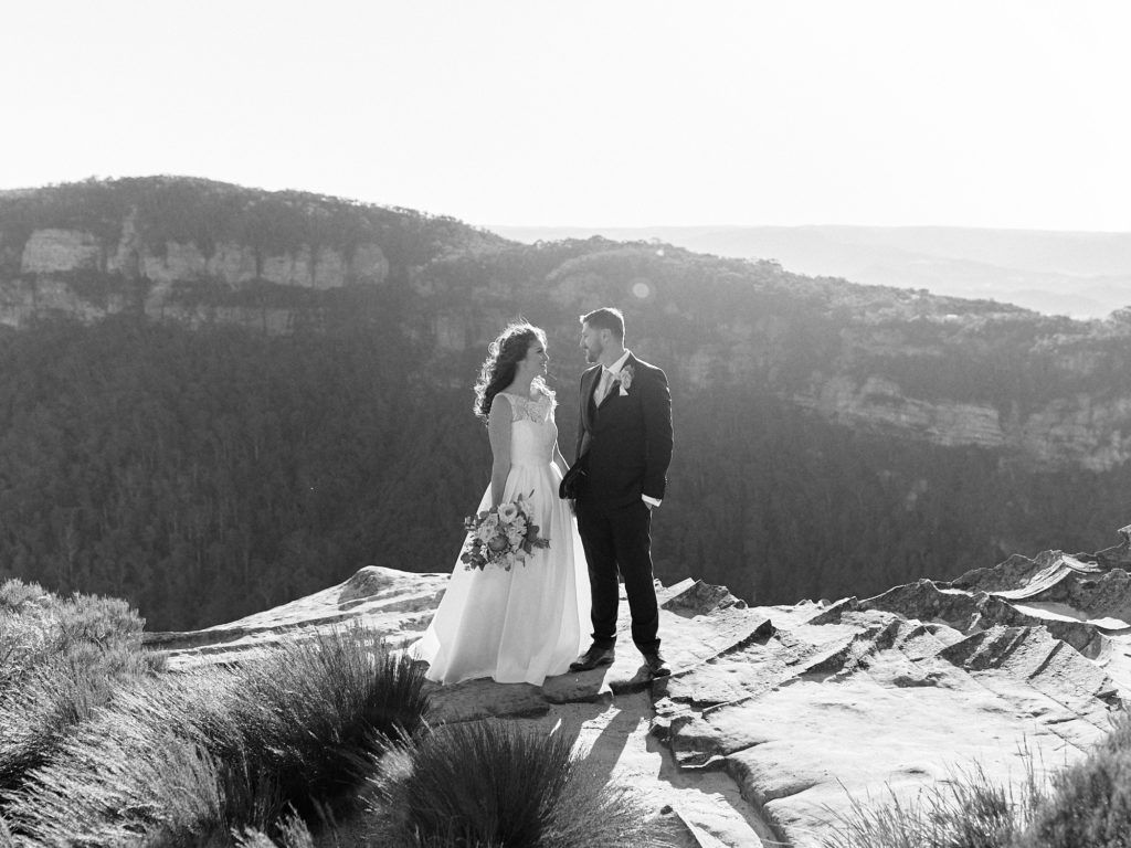 Black and white of newlyweds holding hands at lookout in Blue Mountains