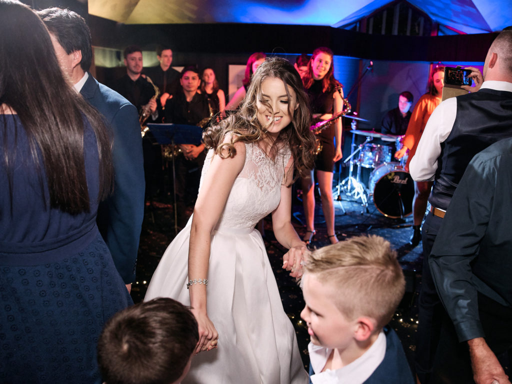 Bride dancing with kids in front of the band during wedding reception